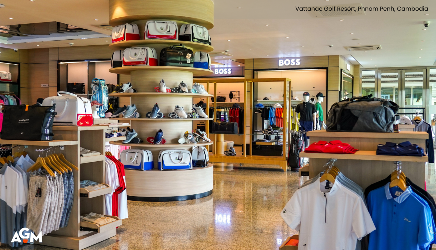 Interior of a golf retail shop at Vattanac Golf Resort in Phnom Penh, Cambodia, featuring a circular display of golf bags and shoes, surrounding racks of apparel, and branded sections including BOSS in the background