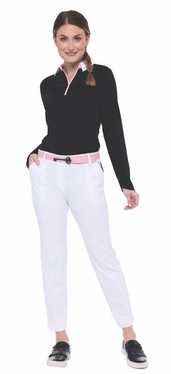 Female golf model wearing a black long-sleeve top with a white collar, white pants, a pink belt, and black golf shoes against a plain background.