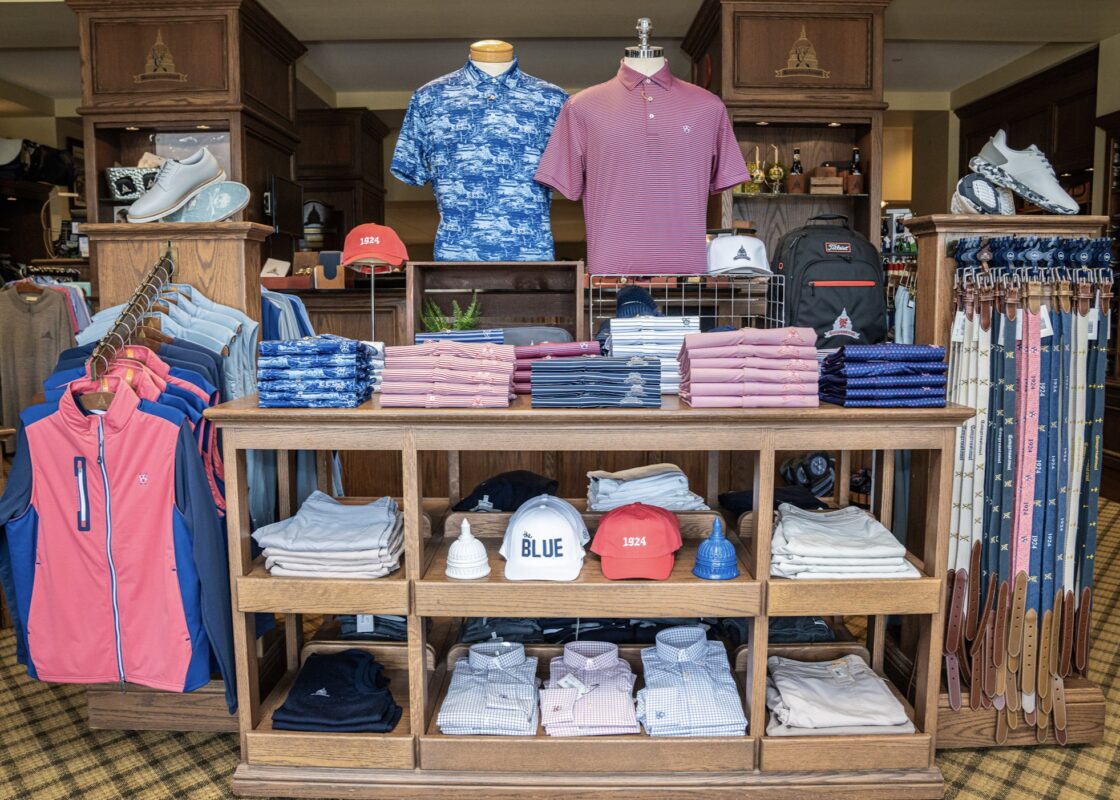 Men’s luxury golf apparel display at Congressional Country Club featuring coordinated lifestyle merchandising of logo polos, technical outerwear, headwear, and accessories.
