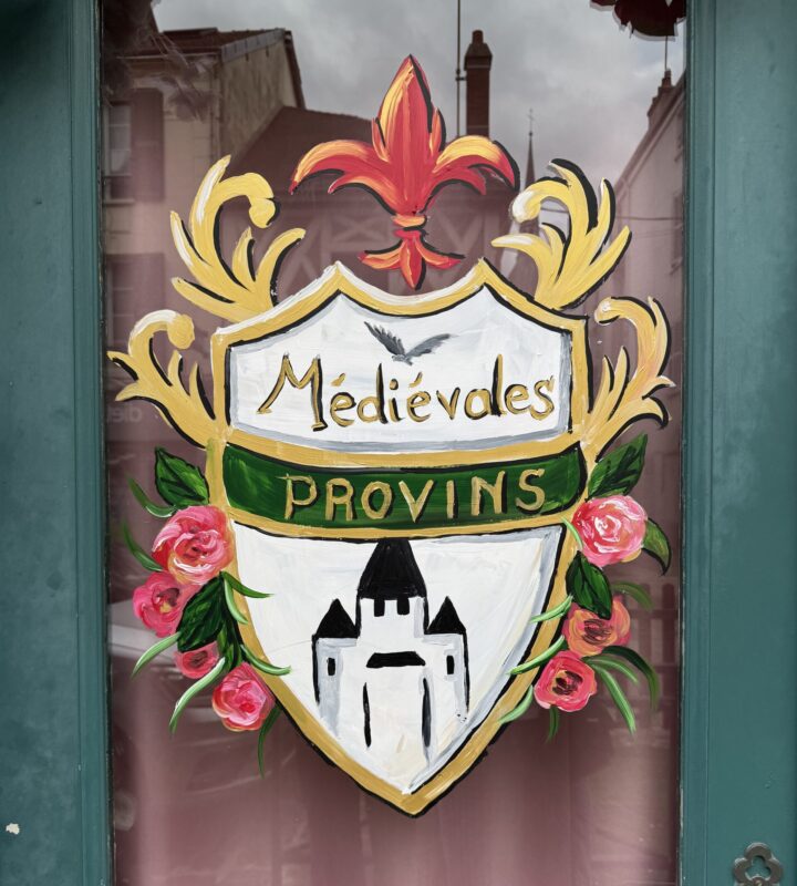 A hand-painted crest on a glass window celebrating "Médiévales Provins."