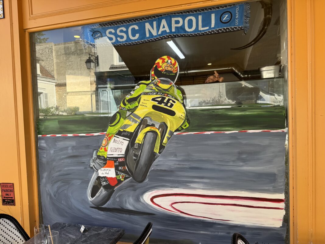 Restaurant window painting of a motorcyclist driving on a track.