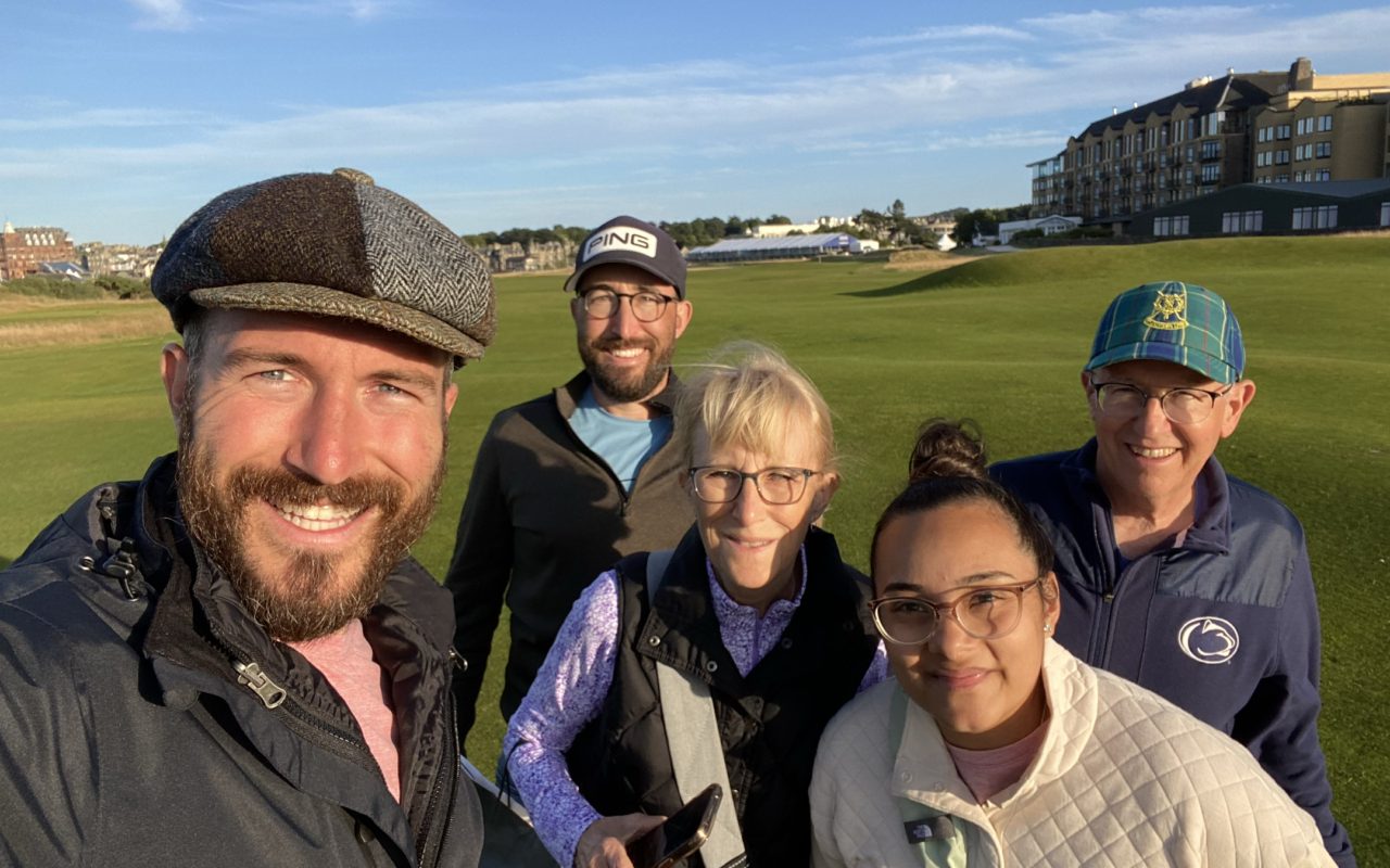 Group of five golfers smiling for a selfie on the greens of St. Andrews Golf and Country Club.