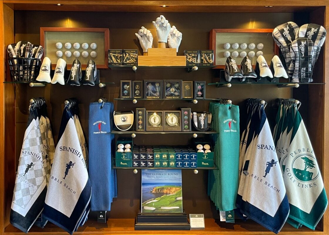 Retail merchandising display at Spanish Bay, Pebble Beach, showcasing branded golf accessories, logo headcovers, and souvenir hard goods.