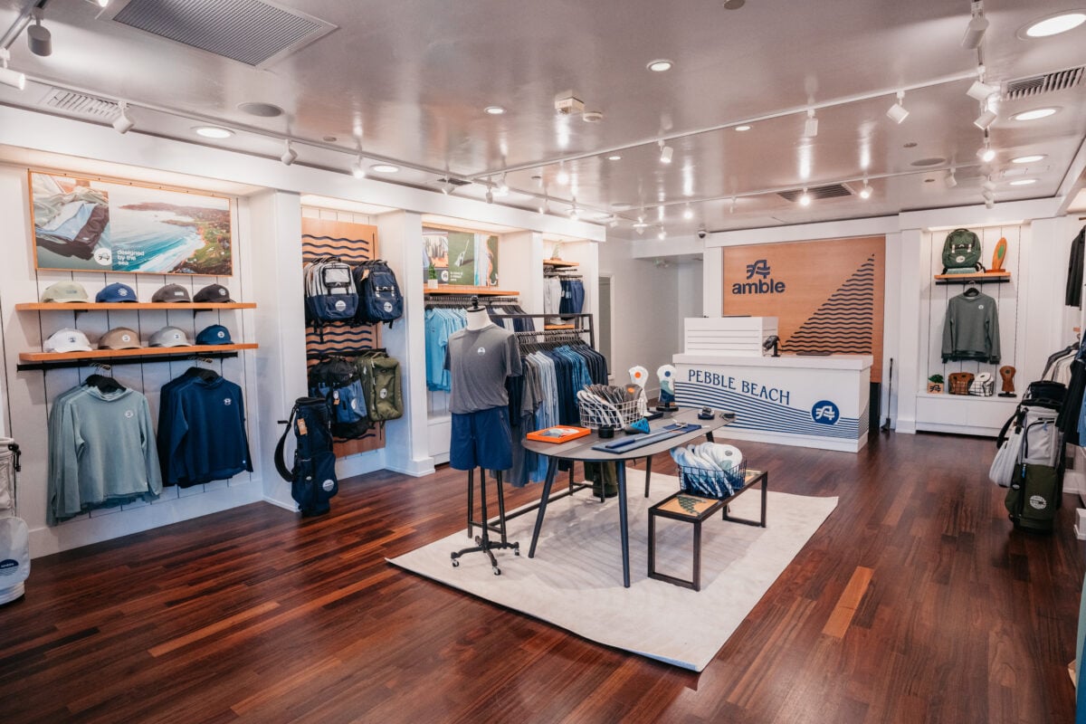 Interior view of the Amble retail space at Pebble Beach featuring coordinated apparel displays, backpacks, golf accessories, and branded checkout fixtures in a modern shop layout.