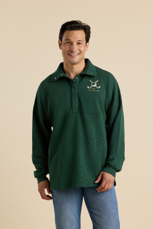 Man modeling dark green oversized collared golf pullover with embroidered crossed golf clubs and “The Dunes” logo on the chest.