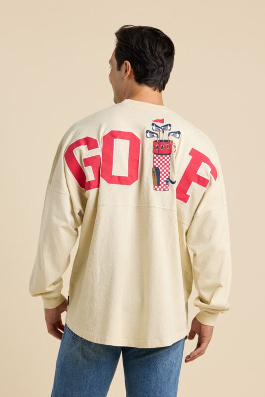 Close-up of embroidered golf bag graphic with checkered pattern and clubs on cream “GOLF” sweatshirt.