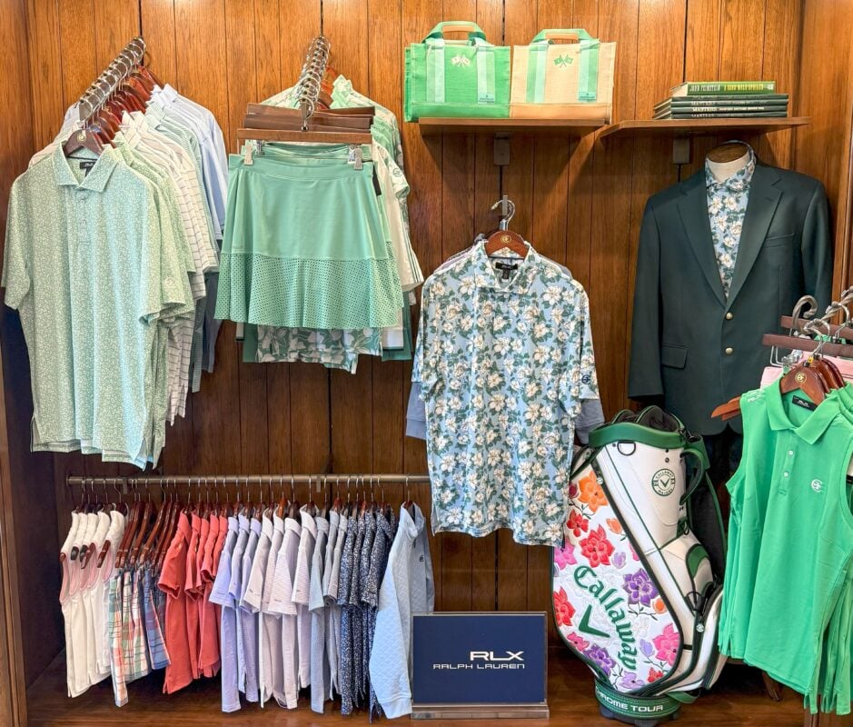 Golf shop merchandise display featuring men’s and women’s apparel in green, blue and coral, alongside a floral Callaway golf bag and Ralph Lauren signage.