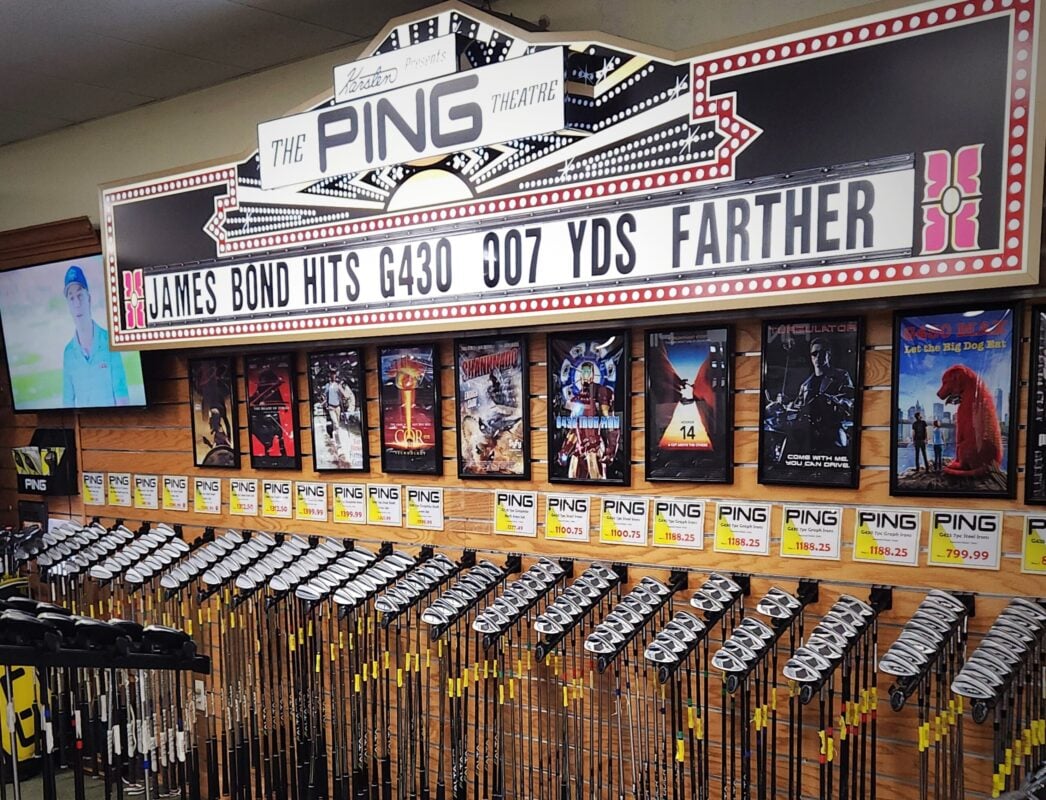 Photo of rows of PING golf clubs displayed beneath a custom movie theater marquee and framed film posters at Haggin Oaks Golf Super Shop.