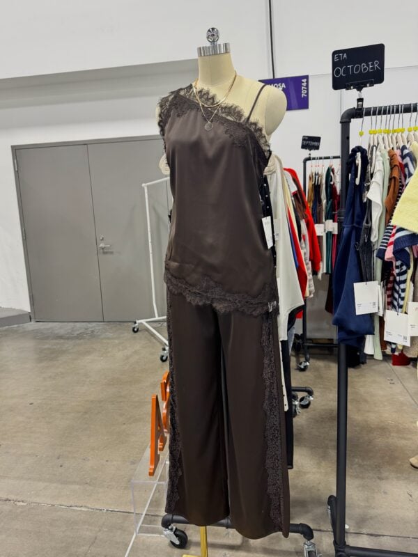 Photo of a mannequin wearing a brown satin camisole and wide-leg pants with lace trim, displayed at a women’s fashion market.
