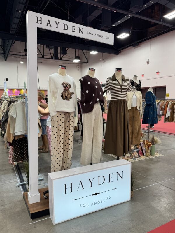 Photo of the Hayden Los Angeles booth at a women’s fashion trade show, with mannequins displaying polka dots, graphic knitwear, wide-leg pants, and layered neutral looks.