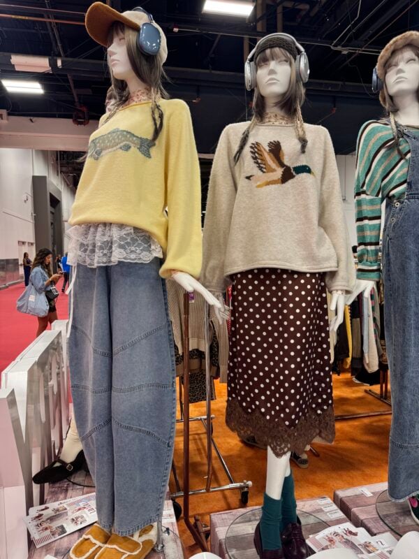 Photo of mannequins at a women’s fashion trade show wearing animal graphic sweaters layered with lace and paired with wide-leg denim and a polka-dot skirt.