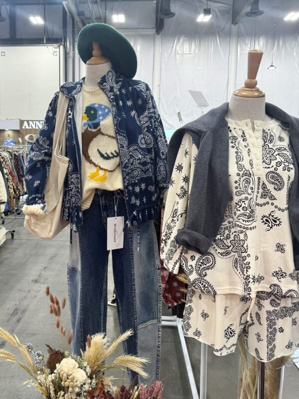 Photo of two mannequins displaying layered women’s fashion, including bandana-inspired prints, a duck graphic sweater, denim, and knit accessories.