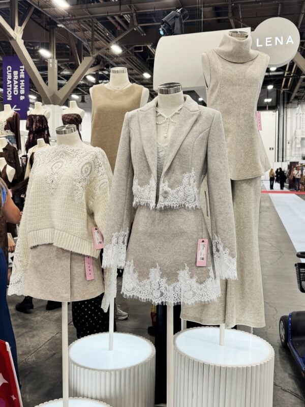 Photo of neutral-toned women’s apparel on mannequins, featuring lace-trimmed sweaters, dresses, and a blazer-and-skirt set at MAGIC 2026.